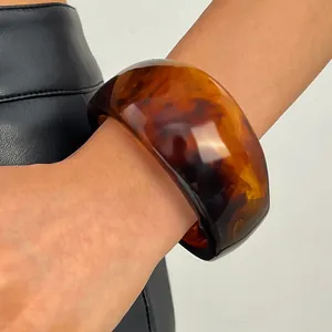 Close-up detail of a vintage amber tortoiseshell resin wide bangle on a female wrist