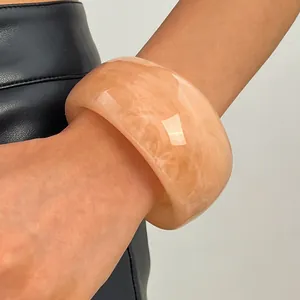 Detailed close-up showing the marbled texture of a peach resin chunky bangle on wrist