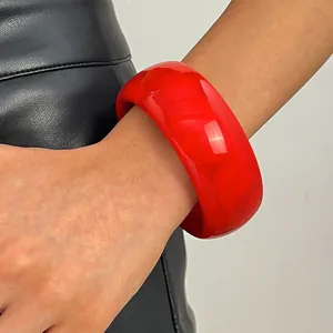 Detailed view of a wide red marbled resin bangle bracelet with a glossy finish.