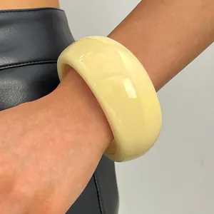 Detailed close-up showing the glossy texture of a vintage wide cream resin bangle on a wrist