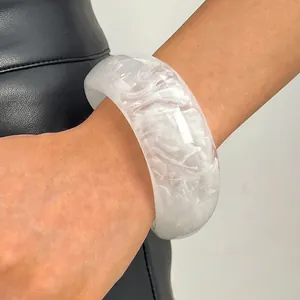Detailed view of wide white marbled resin bangle with artistic smoky acrylic texture