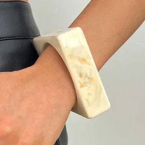 Macro detail shot of a vintage marbled resin wide bangle with cream and beige patterns