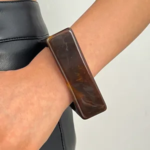Close-up of a vintage marbled resin wide bangle featuring a brown tortoiseshell pattern