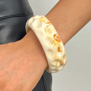 Macro detail of a vintage marbled resin bangle featuring a unique cream and amber dimpled texture