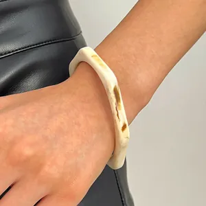 Detail shot of the marbled texture on a vintage cream and brown resin wide bangle bracelet.