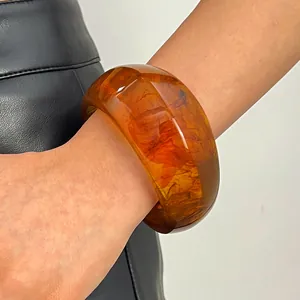 Close-up detail view of a retro marbled resin wide bangle with an amber swirl effect