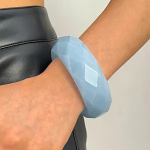 Detail of a light blue faceted acrylic bangle on a wrist