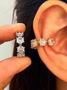 Close-up of gold and silver ear cuffs with three sparkling round cubic zirconia stones.