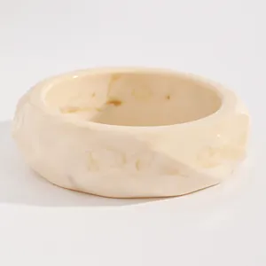Detail view of a retro cream resin bangle with brown marbled patterns and faceted edges