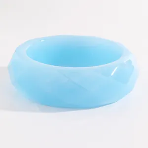Detail view of sky blue wide faceted resin bangle with geometric diamond-cut texture.