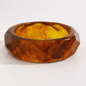 Close-up of vintage amber marbled resin wide bangle with faceted geometric design