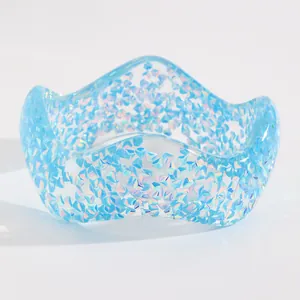 Detail shot of a wide blue resin bangle with iridescent geometric glitter and wavy edges.