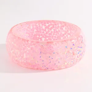 Detailed macro shot of a chunky pink resin bangle featuring iridescent facets