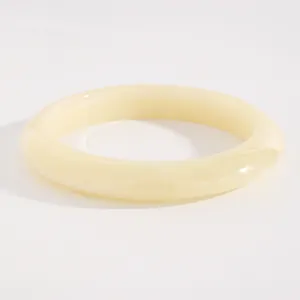 Close-up of a vintage wide resin bangle in creamy yellow with marbled texture