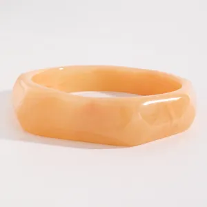 Close-up detail of vintage marbled orange resin wide bangle with elegant faceted design