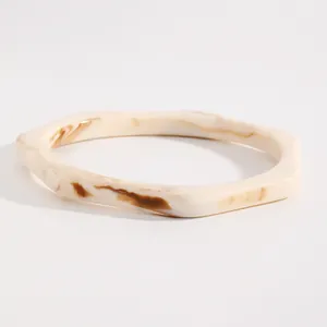 Close-up of a retro marbled resin bangle showing cream and brown swirl patterns.