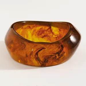 Detailed macro view of a vintage amber resin bangle with dark brown swirl patterns.