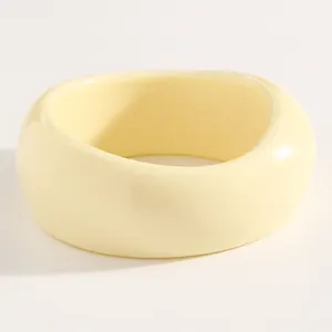 Close-up of a vintage cream-colored chunky resin bangle with a smooth glossy finish.