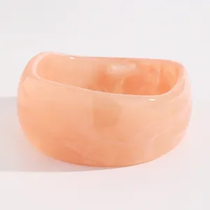 Macro view of vintage marbled acrylic wide bangle with unique wavy edge design in peach