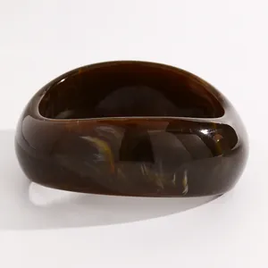 Macro detail view of retro marbled resin wide bangle showing amber texture and glossy finish