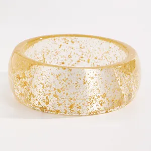 Detailed close-up showing the shimmering gold leaf texture within the wide resin bangle