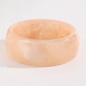Close-up of retro peach marbled resin bangle with a wide, mottled acrylic design