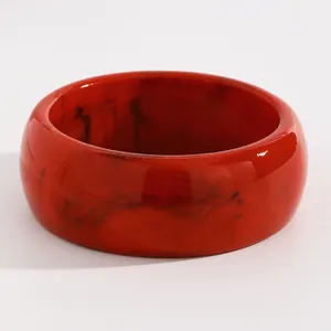Macro view of red marbled resin wide bangle with retro hand-dyed pattern texture