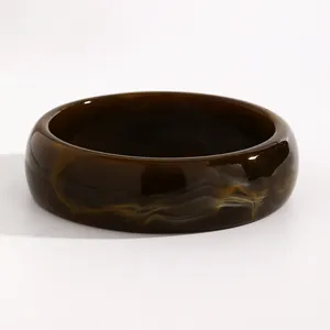 Close-up detail of a dark brown marbled resin wide bangle bracelet with a glossy finish