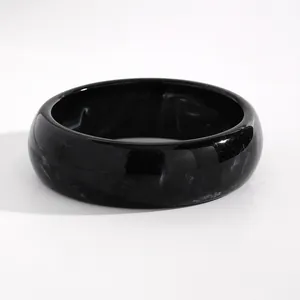 Detailed view of retro black marbled resin wide bangle with polished surface texture