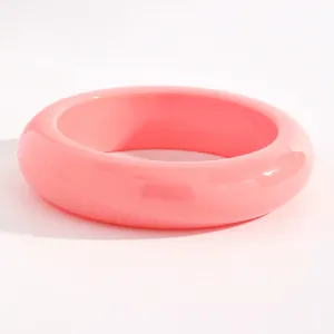 Close-up of smooth pink resin wide bangle bracelet for a retro minimalist look.