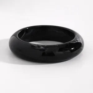 Close-up macro view of a vintage black marbled resin bangle with white swirled pattern