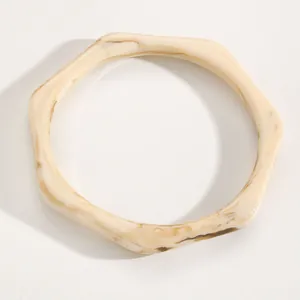 Close-up of a vintage cream-colored resin bangle with brown marble ink-wash pattern