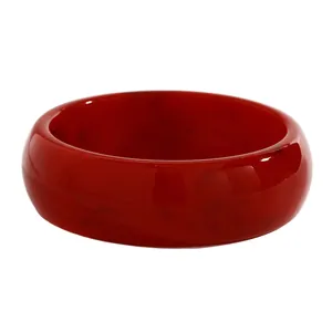 Close-up of a wide red resin bangle featuring a smooth finish and subtle marbled patterns
