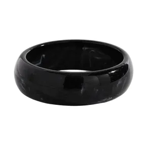 Detailed view of a wide black resin bangle featuring an elegant white marbled ink-wash texture