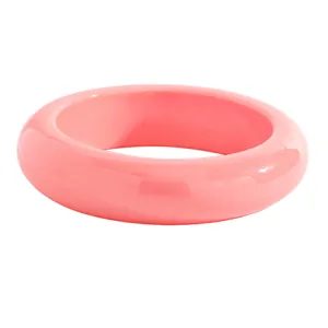 Close-up side view of a chunky pink resin bangle with a glossy smooth finish.