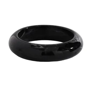 Close-up view of a vintage black resin wide bangle with elegant white marble swirl patterns.