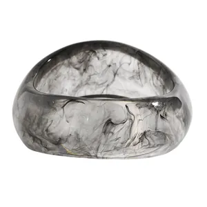 Close-up of retro resin bangle with black ink wash swirl pattern on white background