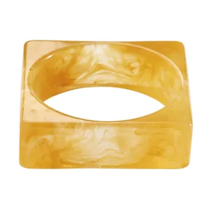 Detail view of an amber marbled resin square bangle with unique cloudy artistic patterns.
