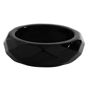 Close-up of a vintage chunky black resin bangle with unique faceted geometric texture