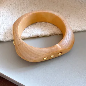 Detailansicht eines Armreifs in Holzoptik mit goldenen Metallnieten und einzigartigem Design