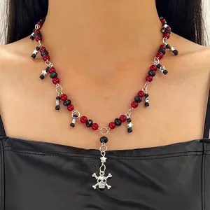 Gros plan d'un collier punk avec perles rouges et noires, tête de mort et étoiles