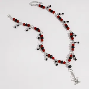 Detail van een punk rode en zwarte kralenketting met ster- en schedelhanger voor dames
