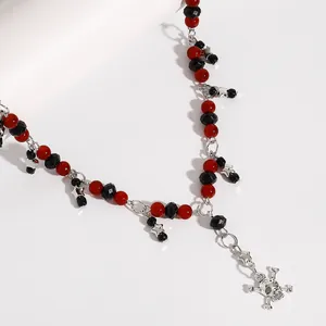 Close-up van gothische punkketting met rode en zwarte kralen en een zilveren schedelhanger