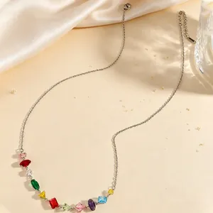 Detailed view of a silver-toned necklace featuring vibrant multi-colored gemstones on a warm background.