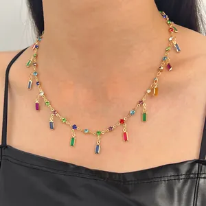 Detailed macro view of a gold-tone collarbone necklace with colorful square gemstone charms