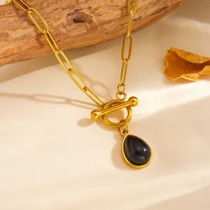 Primo piano di una collana a catena dorata con un elegante ciondolo a goccia nero