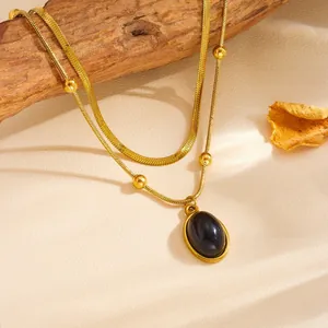 Dettaglio ravvicinato di una collana d'oro a doppio strato con ciondolo ovale in pietra nera