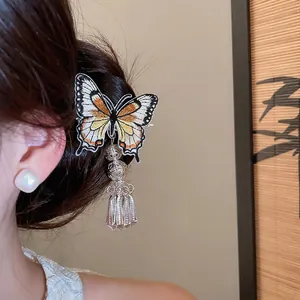 Detailed view of an embroidered butterfly hair clip with metallic tassels and bells