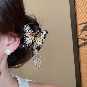 Close-up detail of a vintage style butterfly embroidered hair clip with metallic bell tassels