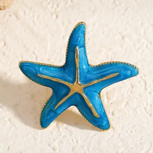 Nahaufnahme einer blauen Emaille-Seestern-Brosche mit goldfarbenen Ozean-Details